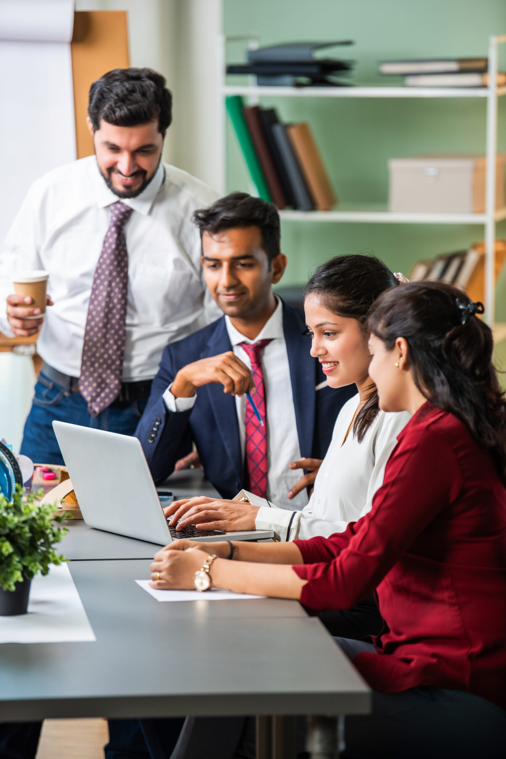 Young Indian Asian Leader Coach Teaching Employees Group Analyzing Online Project Explaining Business Strategy Speaking Training Diverse Corporate Team With Laptop Using Computer At Office Meeting